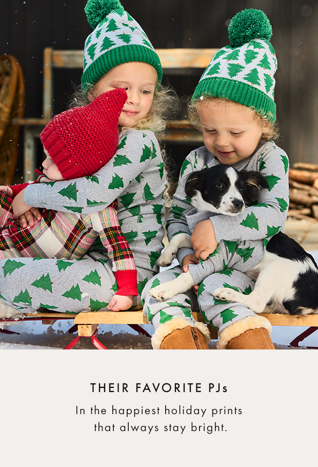 three kids and a dog wearing matching holiday pajamas